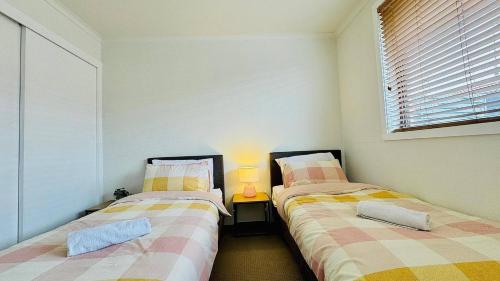 two beds sitting next to each other in a room at Cozy 2BR Retreat, 3-Minute Drive to Albury Airport in Albury