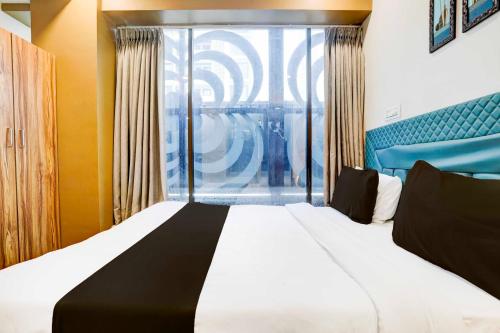 a bedroom with a large bed and a window at Hotel O Vesu Surat in Surat