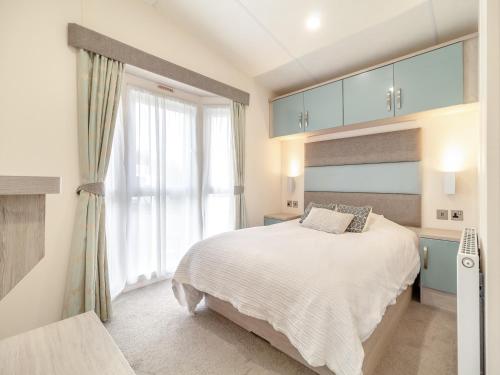 a bedroom with a bed and a large window at Osprey 52 in Saxmundham