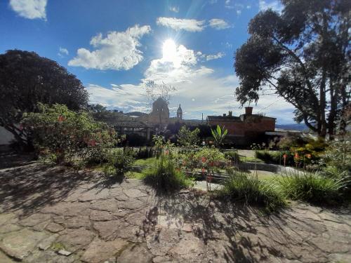a garden with flowers and the sun in the sky at Hotel Pueblo Dorado Sesquilé in Sesquilé