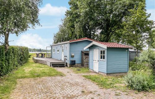 a blue shed with a bench next to a dirt road at 2 Bedroom Nice Home In Lauwersoog in Lauwersoog