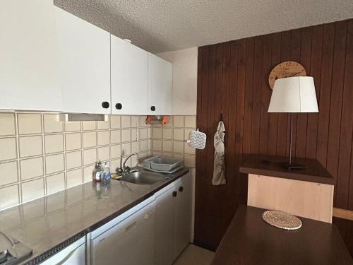 La cuisine est équipée de placards blancs, d'un évier et d'une lampe. dans l'établissement Appartement confort pour 4/6 pers. au cœur de la station avec terrasse - FR-1-814-140, à Besse-et-Saint-Anastaise