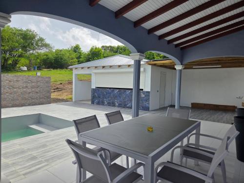 a patio with a table and chairs on a deck at Les Villas de Boisvin in Le Moule