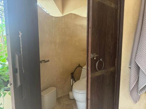a small bathroom with a toilet and a door at V222 Zen Sea View Villa Pool, Hot Tub & Chess in Plai Laem