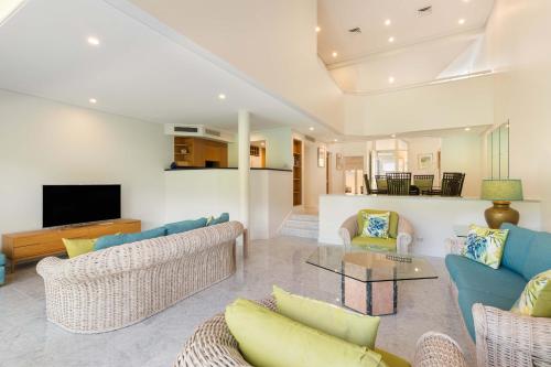 sala de estar con sofás azules y TV en Mirage Resort Villa 138 with access to Sheraton Facilities, en Port Douglas