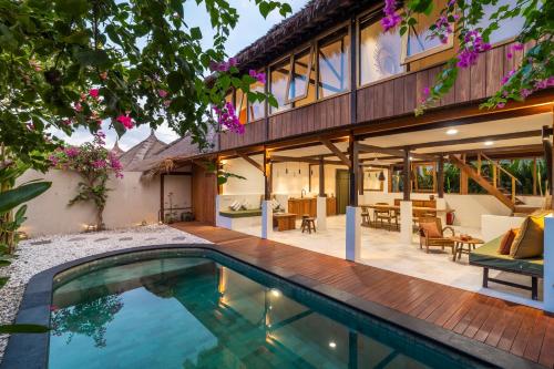 an external view of a house with a swimming pool at Villa Tiga in Gili Air