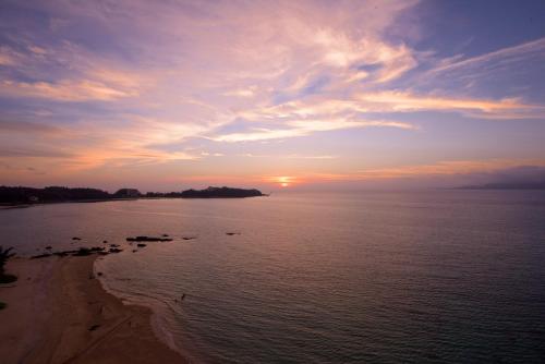 a sunset over the water with birds on the beach at Best Western Okinawa Kouki Beach in Nago