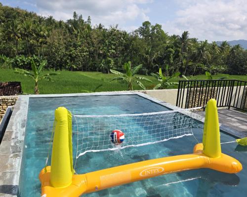 a pool with a ball in the net at Villa Norwegia - pool with panorama rice field view in Yogyakarta