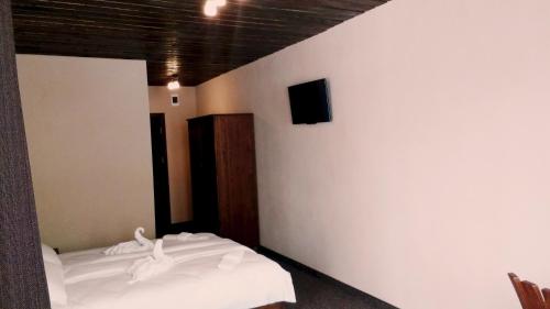 a bedroom with two beds and a tv on a wall at Family hotel Valchanovata Kashta in Fotinovo