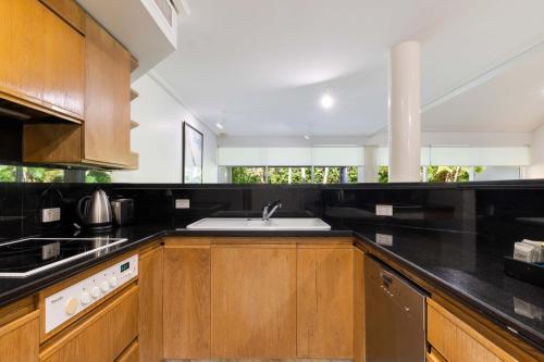 Una cocina con gabinetes de madera y un fregadero. en Mirage Resort Villa 144 with access to Sheraton Facilities, en Port Douglas