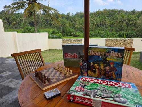 a table with a chessboard and a book on it at Villa Norwegia - pool with panorama rice field view in Yogyakarta