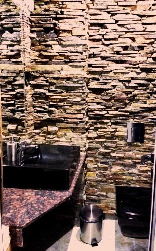 a stone bathroom with a sink and a stone wall at Family hotel Valchanovata Kashta in Fotinovo