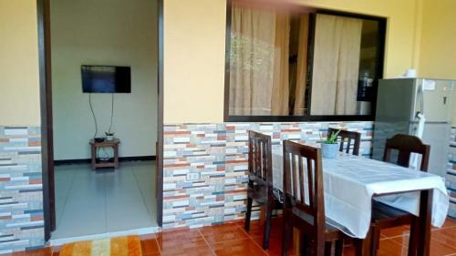 a dining room with a table and chairs and a television at Tropical Garden Apartment in Moalboal