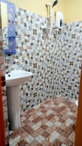 a bathroom with a sink and a tiled wall at Tropical Garden Apartment in Moalboal