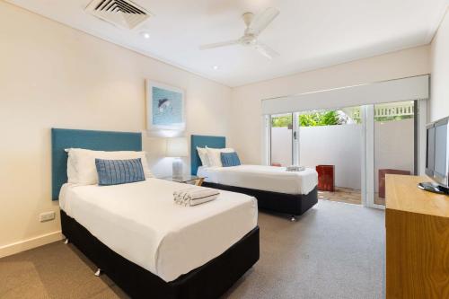 Un dormitorio con dos camas y un televisor de pantalla plana. en Mirage Resort Villa 146 with access to Sheraton Facilities, en Port Douglas