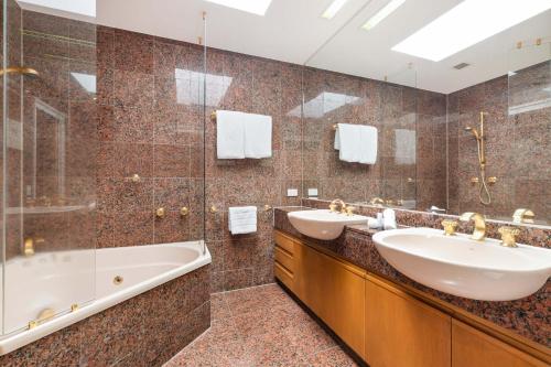 Un baño con dos lavabos, una bañera y una ducha. en Mirage Resort Villa 146 with access to Sheraton Facilities, en Port Douglas