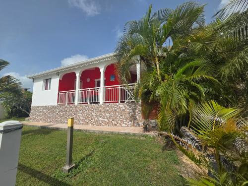 a house with red windows and a palm tree at Les Villas de Boisvin in Le Moule