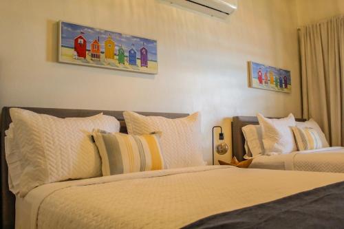 a bedroom with two beds and paintings on the wall at Villa Las Tres Gaviotas I in Salinas
