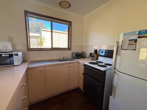 a kitchen with a white refrigerator and a stove at Alwyns By The Sea in Inverloch