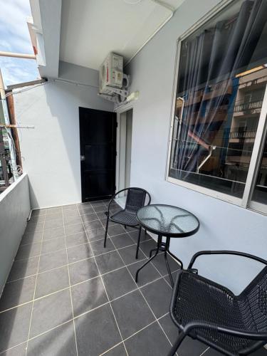 a balcony with two chairs and a table and a window at Tin Guest House & Laundry in Jomtien Beach