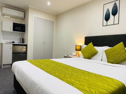 a bedroom with a large bed with a yellow blanket at Bakers Lodge in Auckland