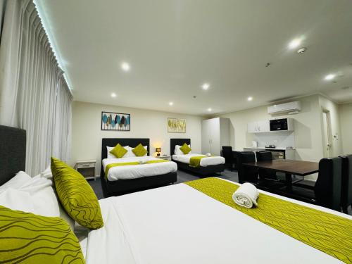 a hotel room with two beds and a table at Bakers Lodge in Auckland