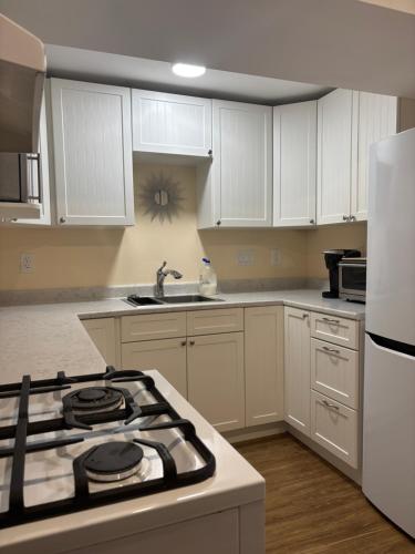 a kitchen with white cabinets and a stove top oven at Comox Valley Guest House in Comox