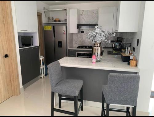 a kitchen with a counter with chairs and a vase of flowers at Villa Familiar con Piscina en VistaCana in Punta Cana
