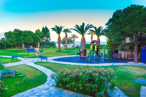 a playground in a park with palm trees at Ephesia Hotel - All Inclusive in Kusadası