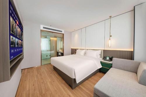 a bedroom with a large white bed and a couch at Shanshui Trends Hotel-Bantian Dong Branch in Shenzhen
