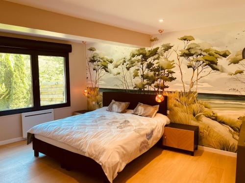 a bedroom with a bed with a painting on the wall at Villa La perle des Sylves in Neufchâtel-Hardelot