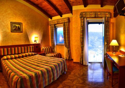 a bedroom with a bed and a desk and a window at Hotel La Bussola in Orta San Giulio