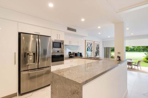 a kitchen with stainless steel appliances and white cabinets at Mirage Resort Villa 422 with access to Sheraton Facilities in Port Douglas