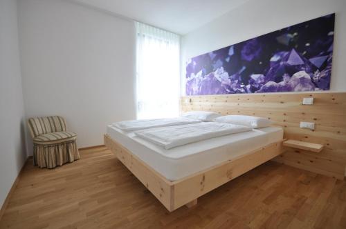 a bedroom with a bed and a large painting on the wall at Alpenchalet Apartments in Parcines