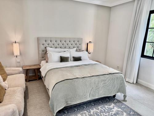 a white bedroom with a large bed and a couch at VILLA SCALINA Seaside Hideaway - 7 Bedroom - Pool - Gym - Walk to beach in Calodyne