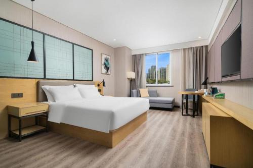 a hotel room with a large bed and a television at Echarm Hotel Yingshang High-speed Railway Station Wuzhou Wanhui Plaza in Fuyang