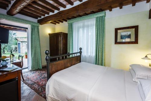 a bedroom with a large bed and a television at Villa Acquaviva Wine Resort in Montemerano