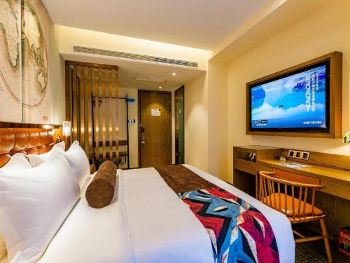 a hotel room with a bed and a flat screen tv at James Joyce Coffetel· Xianyang Renmin Road Central Square Store in Xianyang