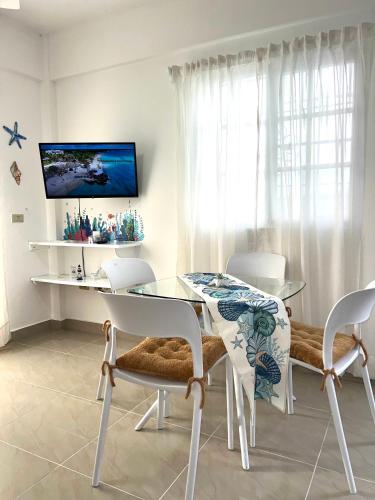 a dining room with a glass table and white chairs at Apartamento a solo pasos del centro y la playa in Bayahibe