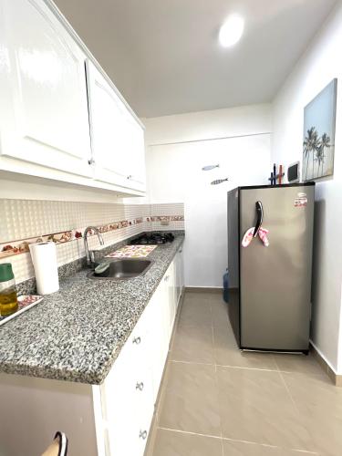 a kitchen with a stainless steel refrigerator and white cabinets at Apartamento a solo pasos del centro y la playa in Bayahibe
