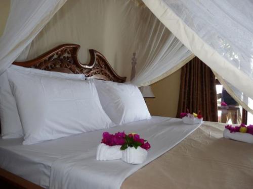 ein Bett mit zwei weißen Kissen und Blumen darauf in der Unterkunft Pemba Misali Sunset Beach in Wesha