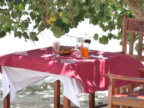 Pemba Misali Sunset Beach في Wesha: طاولة عليها قماش الطاولة الحمراء والمشروبات