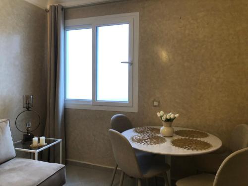 a room with a table and chairs and a window at Darkoum Apartment Anza in Agadir