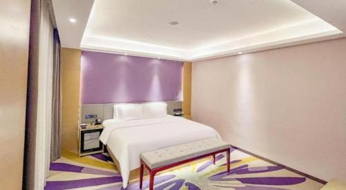 a bedroom with a white bed and a purple wall at Lavande Hotel Huizhou Shiwan in Huizhou