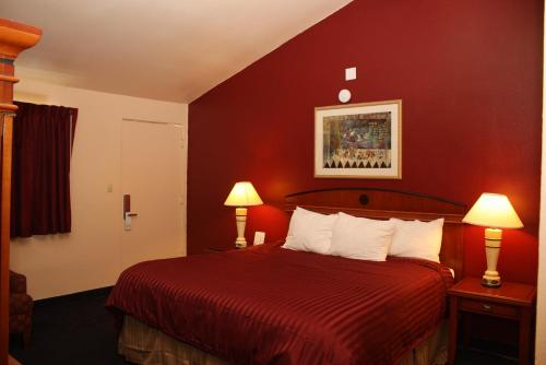 a hotel room with a red bed with two lamps at Budget Inn in San Luis Obispo