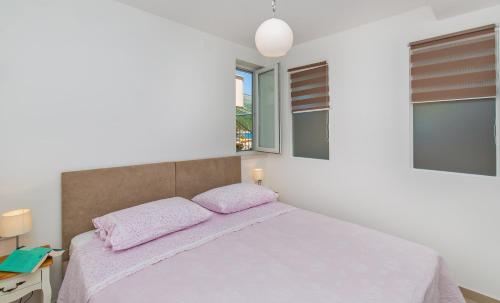 1 dormitorio con 1 cama con sábanas rosas y ventanas en Apartments Marija Lapad, en Dubrovnik