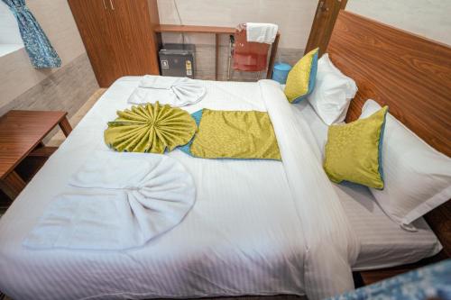 a large white bed with yellow pillows on it at Hotel Mirka Plaza in Bhubaneshwar