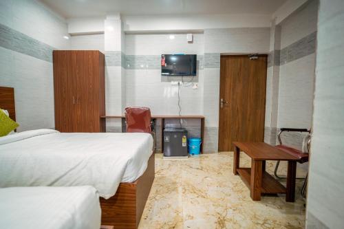 a room with two beds and a table and a tv at Hotel Mirka Plaza in Bhubaneshwar