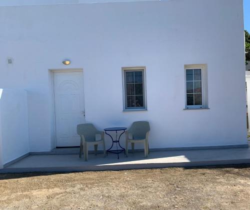 two chairs and a table in front of a white building at Nηρηις in Agia Marina