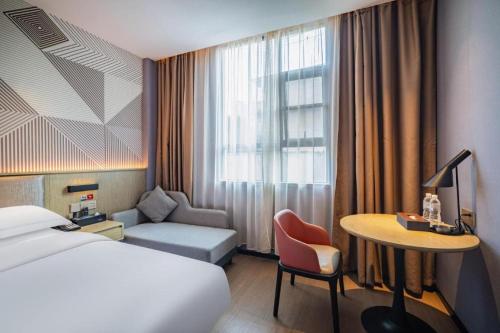 WuzhouにあるBorrman Hotel Wuzhou College Fumin Roadのベッドと机とテーブルがあるホテルの部屋